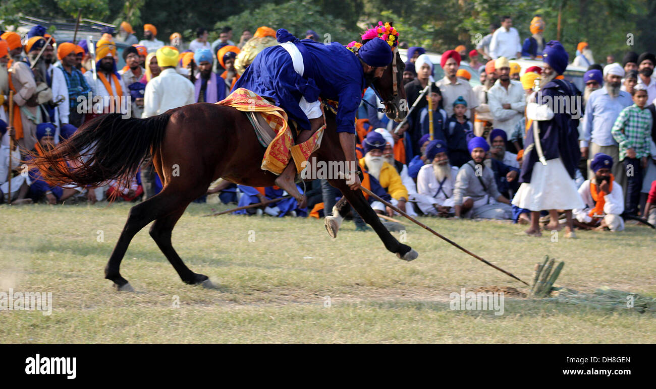 Sikh Krieger oder Nihang führt Pferd Reiten Fähigkeiten zusammen mit militärischen Fähigkeiten während ein Mohalla in Amritsar. Stockfoto