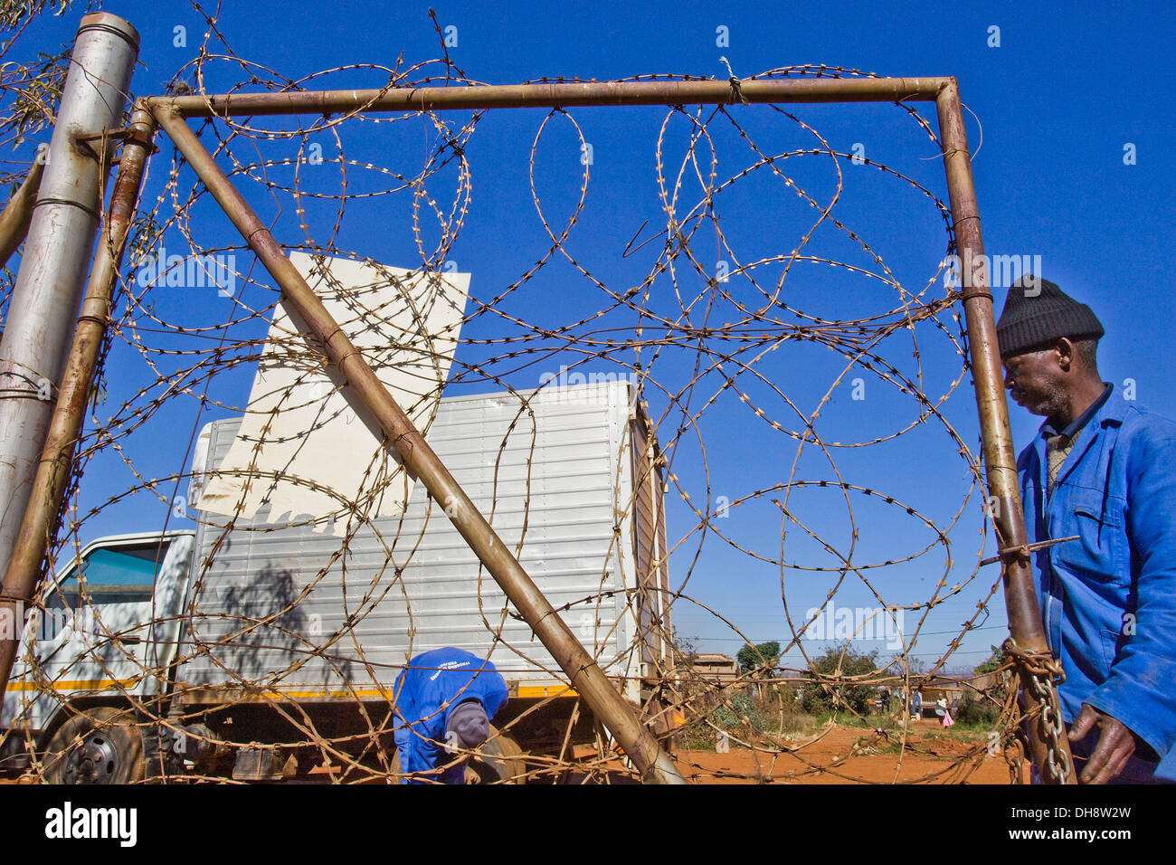 Ein Arbeiter öffnet ein Stacheldraht-Tor bei der Müllabfuhr-Seite von Ziegeln Mokolo in Orange Farm betrieben. FIFA WM 2010 in Stockfoto