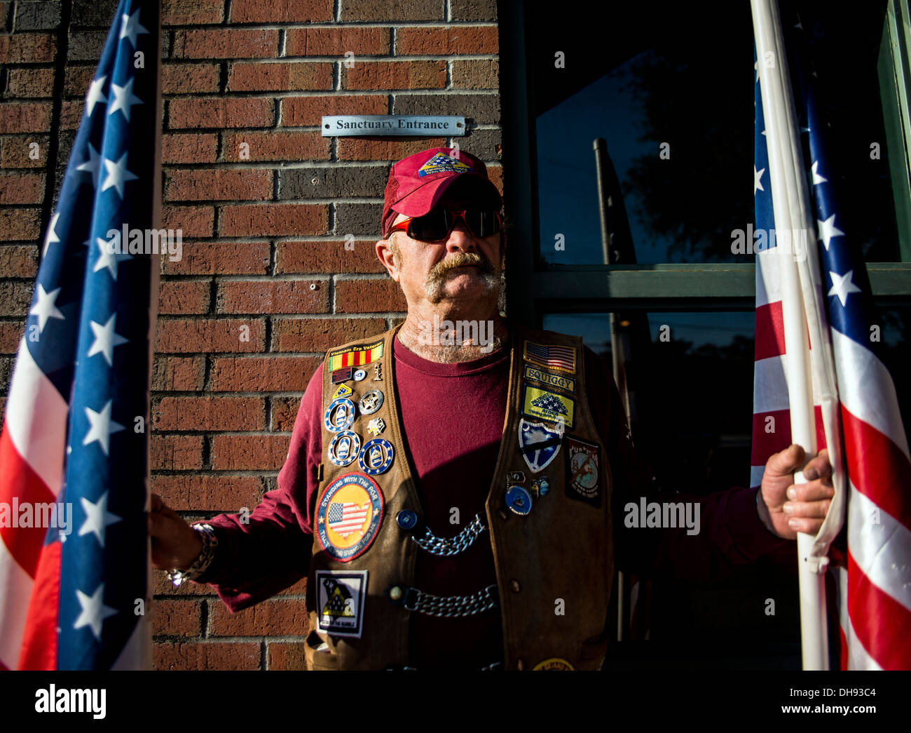 South Carolina Patriot Guard Mitglied hat amerikanische Flaggen außerhalb der gemeinsamen Basis Charleston - Air Base Kapelle während der Trauerfeier im Ruhestand Master Sgt. Dave Williams 30. Oktober 2013. Williams diente als Basis Multimedia-Manager und Chef der inte Stockfoto