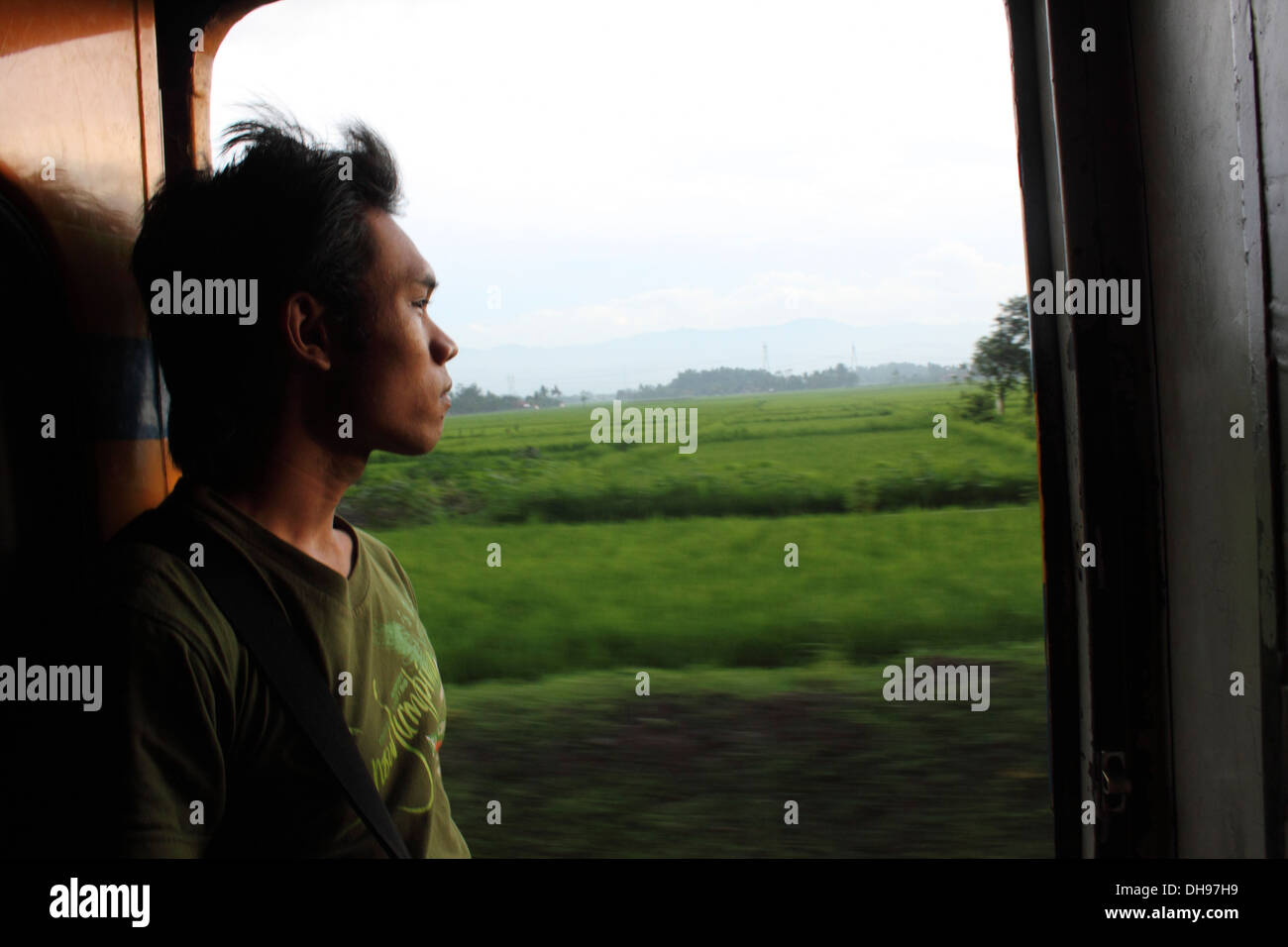 Junger Mann aus der Tür von einem fahrenden Zug suchen; Java, Indonesien Stockfoto