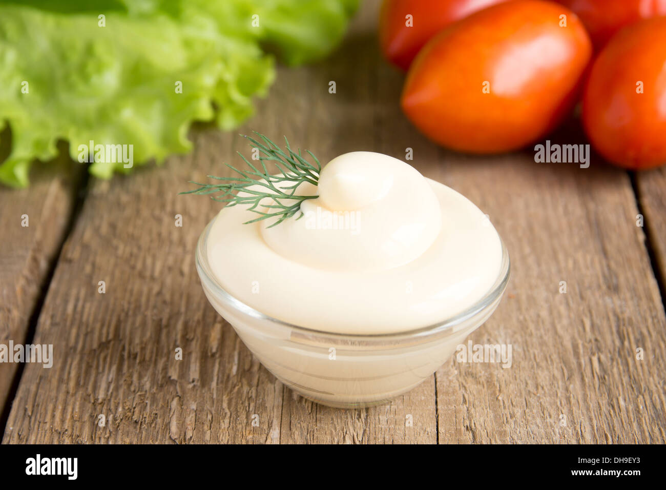 Frische leckere Mayonnaise-Sauce in Schüssel mit Gemüse (Tomaten, Salat) auf rustikalen hölzernen Hintergrund, Nahaufnahme, horizontale Stockfoto