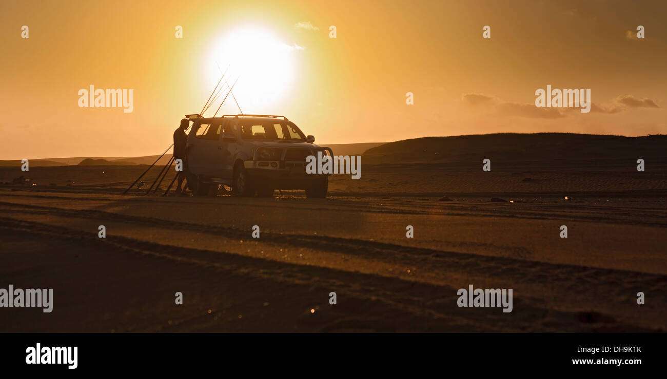 Panoramablick über den Strand Sanddüne Geländestrecke mit geparkten 4wd Fahrzeug bei Sonnenuntergang mit Vorbereitung Angelruten gegen Fischer Stockfoto