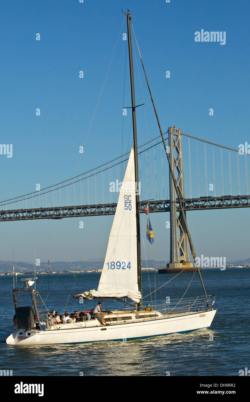 Segelyacht, Yukon Jack, kehrt mit der Bay Bridge im Hintergrund, San Francisco. Stockfoto