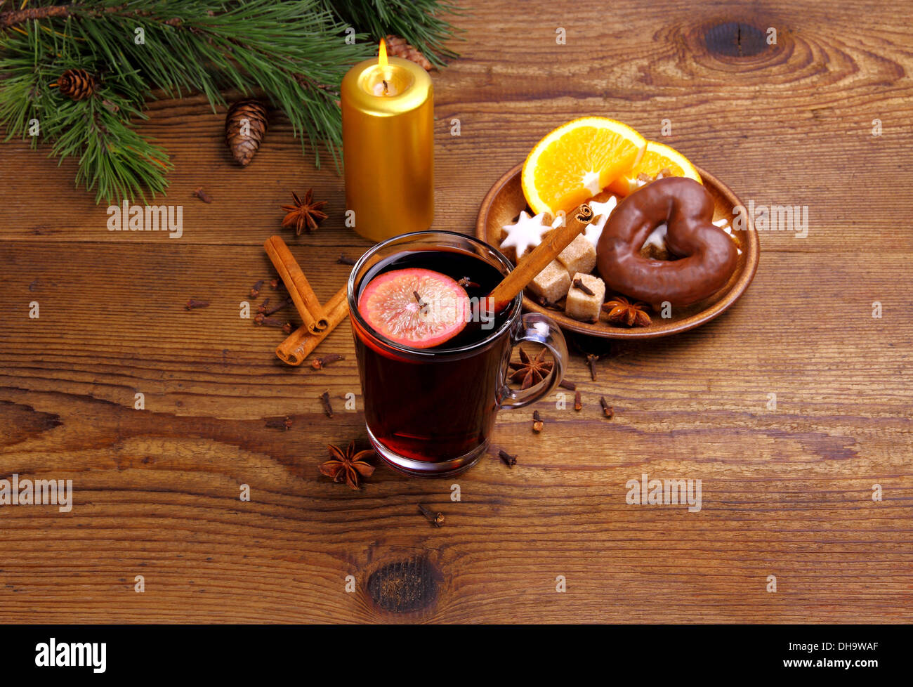 Glühwein in Glas mit Zimtstange, Kerze und Süßigkeiten, horizontale Stockfoto