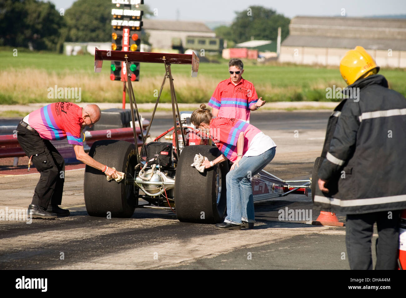 Crew-Mitglieder, die Reinigung der Slick-Rennreifen auf einem Dragster vor einem Lauf Stockfoto