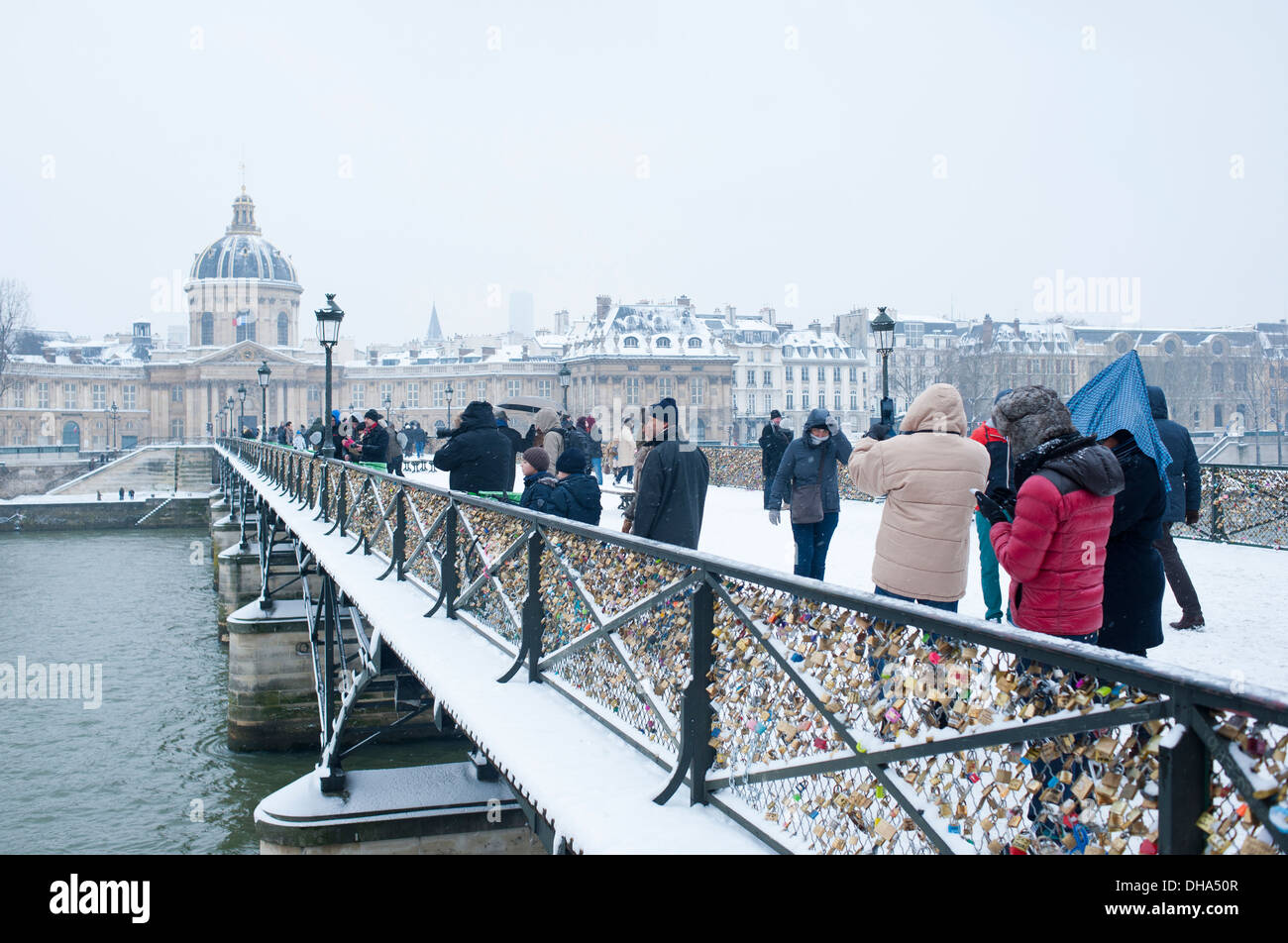 Paris, Frankreich - Menschen auf der Pont des Arts an einem verschneiten Tag im Winter Stockfoto