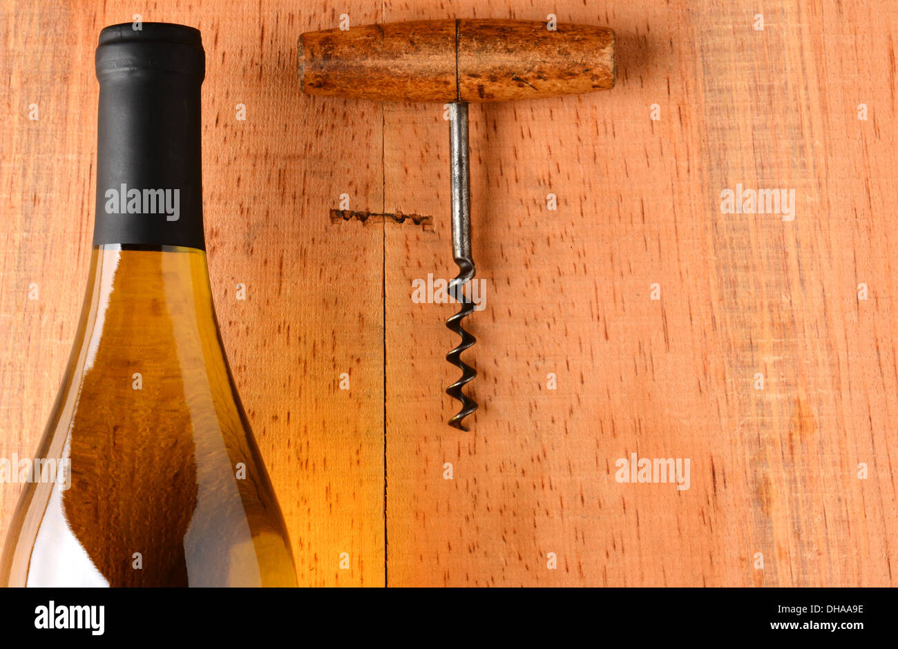 Nahaufnahme eines Chardonnay Wein Flasche und Korkenzieher auf rustikale Oberfläche des Holzes. Die Flasche hat keine Bezeichnung Stockfoto