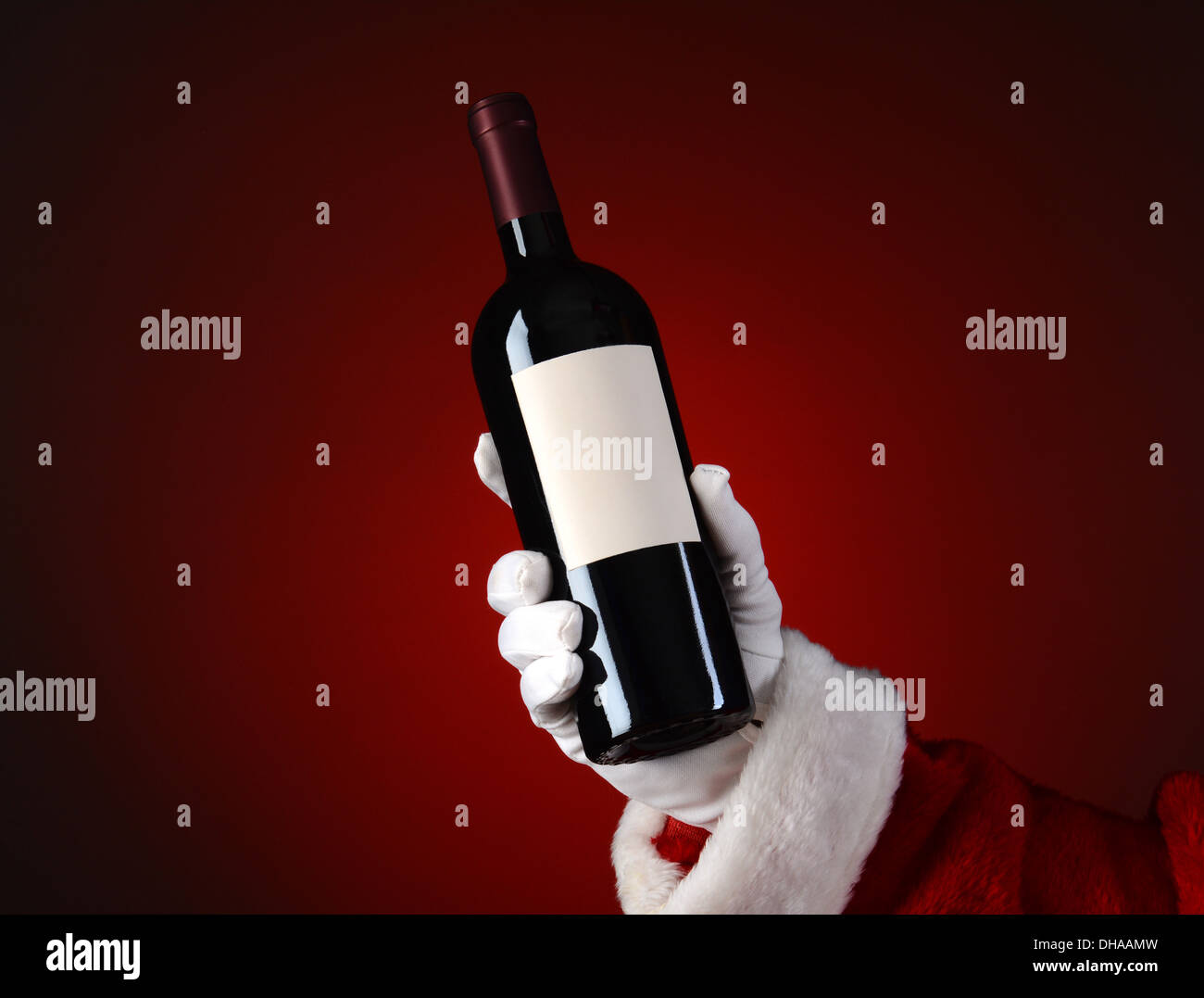 Nahaufnahme von Santa Claus mit einer Flasche Wein in der Hand. Hand und Arm nur über eine leichte bis dunkelroten Fleck Hintergrund. Stockfoto