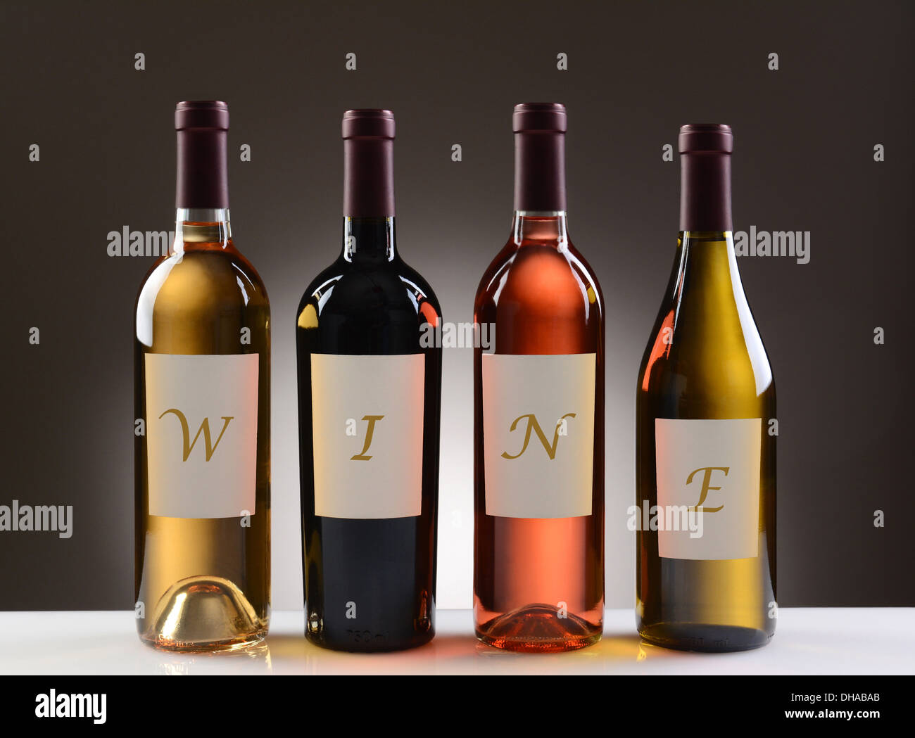 Vier Weinflaschen mit ihren Etiketten, Rechtschreibung, das Wort Wein, auf eine leichte bis dunkelgrauen Hintergrund. Stockfoto