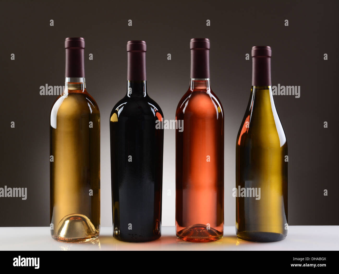 Vier Weinflaschen mit keine Etiketten auf ein Licht, dunkelgrauen Hintergrund. Stockfoto