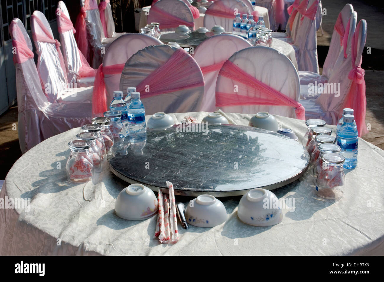Tabellen sind formell und Stühle sind in rosa Bändern für ein bevorstehendes Ereignis auf einer Stadtstraße in Kampong Cham, Kambodscha drapiert. Stockfoto