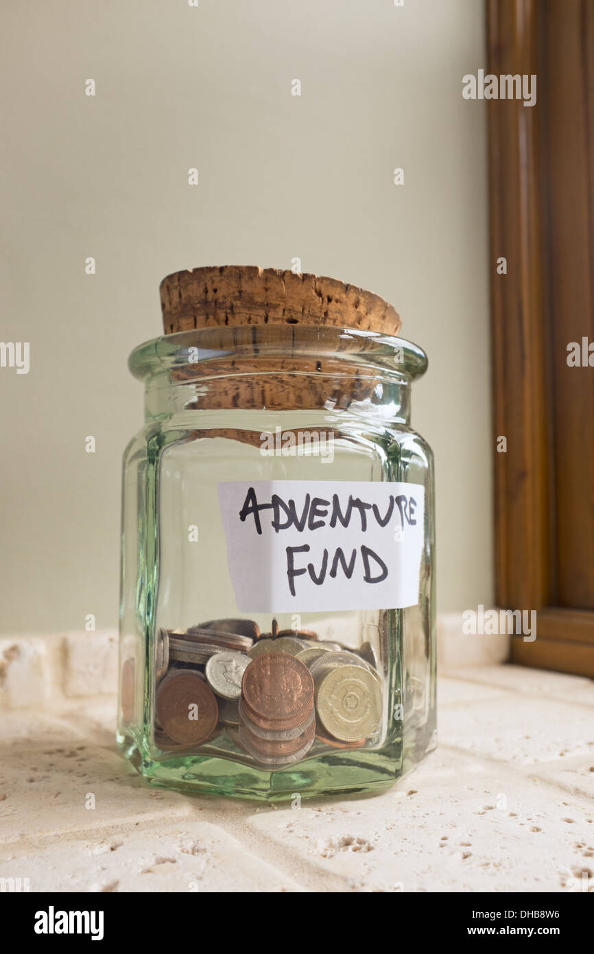 Glas mit der Aufschrift Abenteuer Fonds mit Kleingeld. Stockfoto