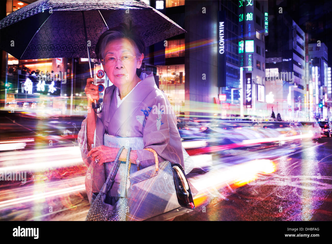 Eine chinesische Frau Alter 50-60 Fuß mit einem Regenschirm in der Nacht in den Straßen von Tokio, Japan. Das Bild ist Farbe. Stockfoto