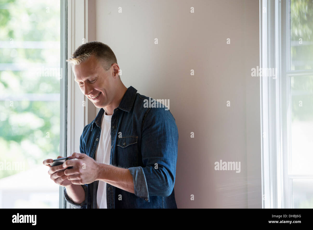 Ein Mann steht in einer ruhigen Ecke ein Café, ein smart Phone verwenden. Stockfoto