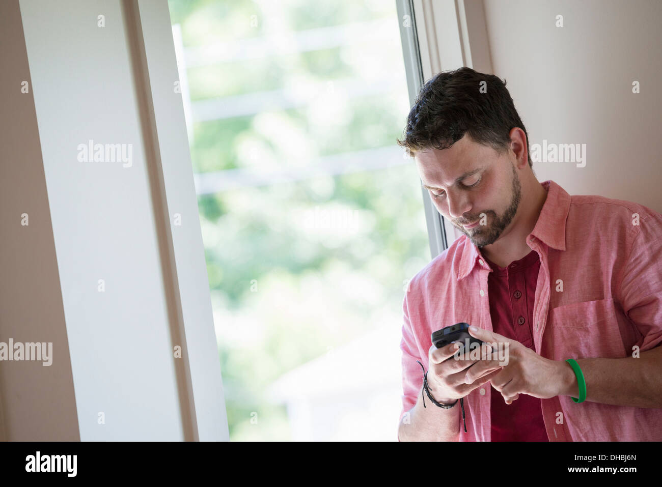 Ein Mann steht in einer ruhigen Ecke ein Café, ein smart Phone verwenden. Stockfoto
