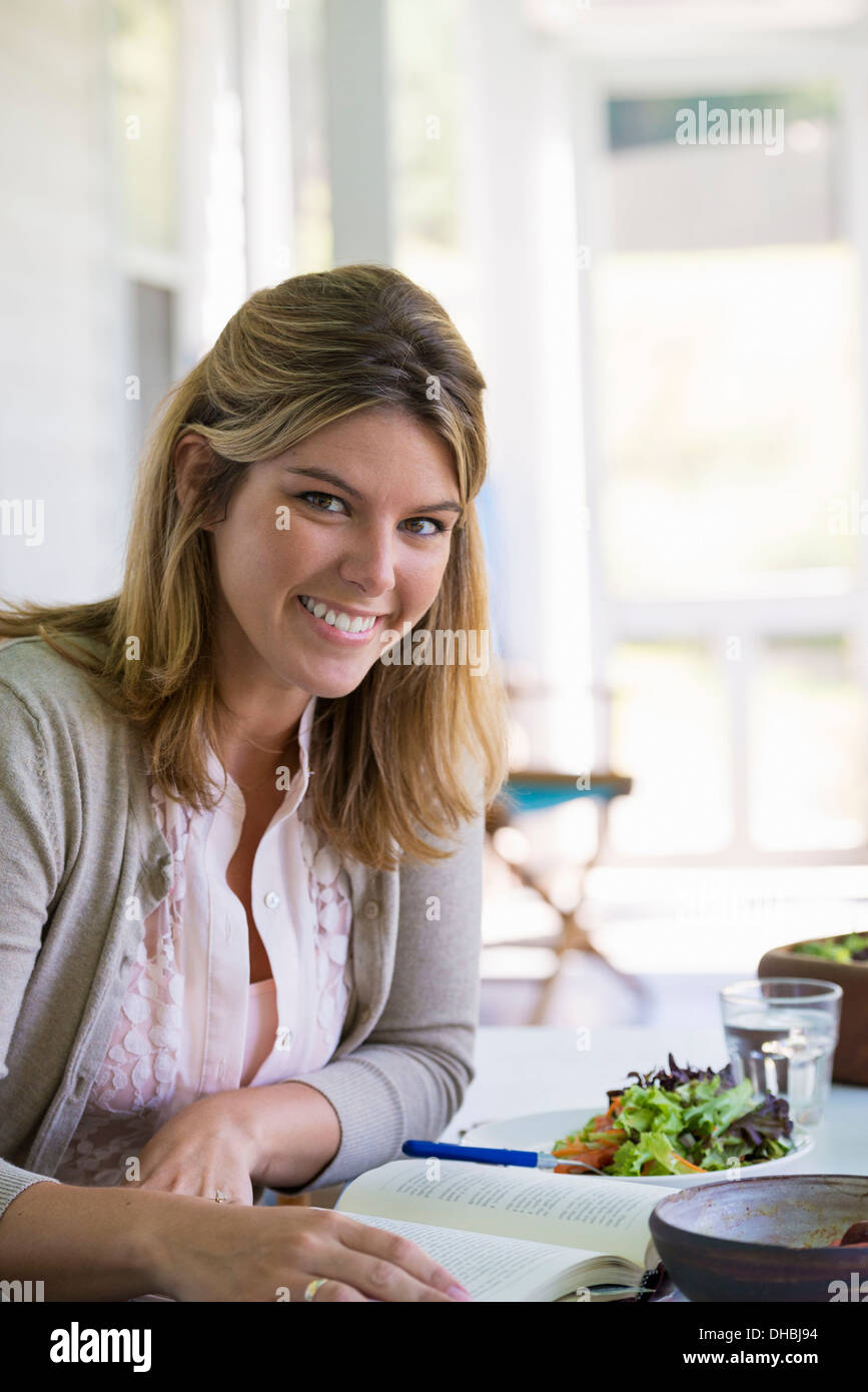 Eine Frau sitzt an einem Tisch, ein Buch zu lesen. Stockfoto