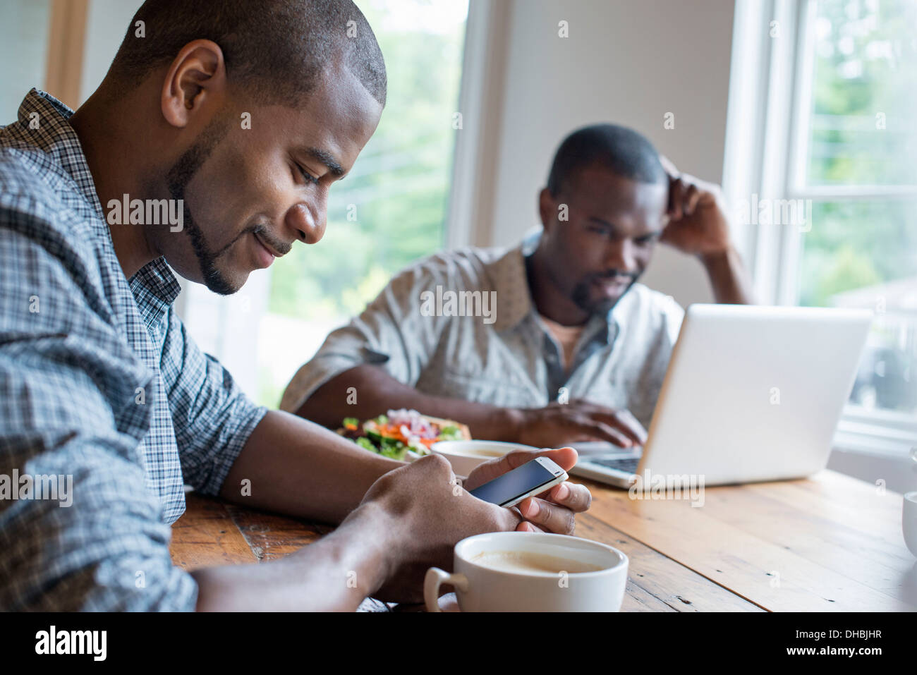 Zwei Männer sitzen in einem Café. Verwenden einen Laptop und ein smart Phone. Stockfoto