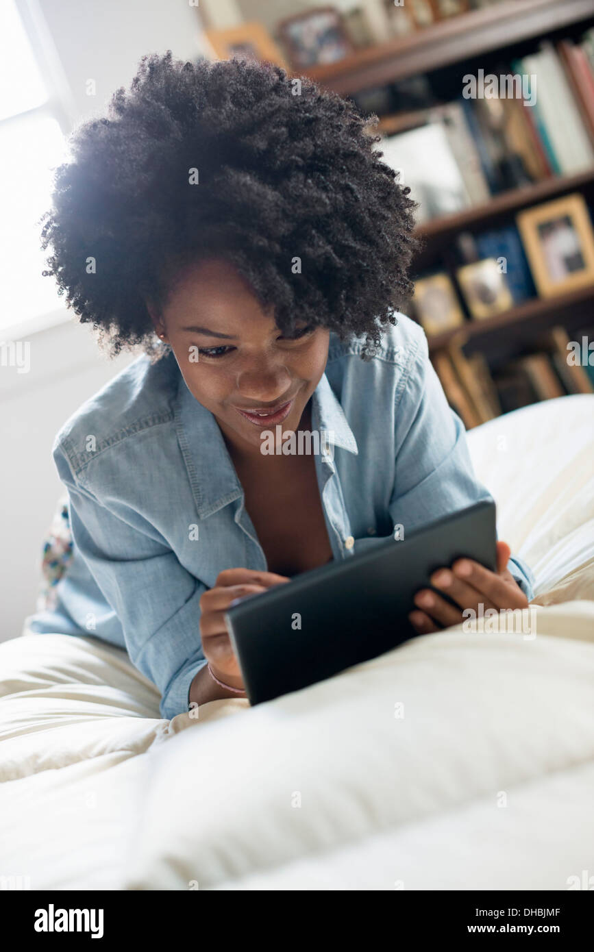 Eine Frau auf einem Bett liegend mit einem digitalen Tablet. Stockfoto