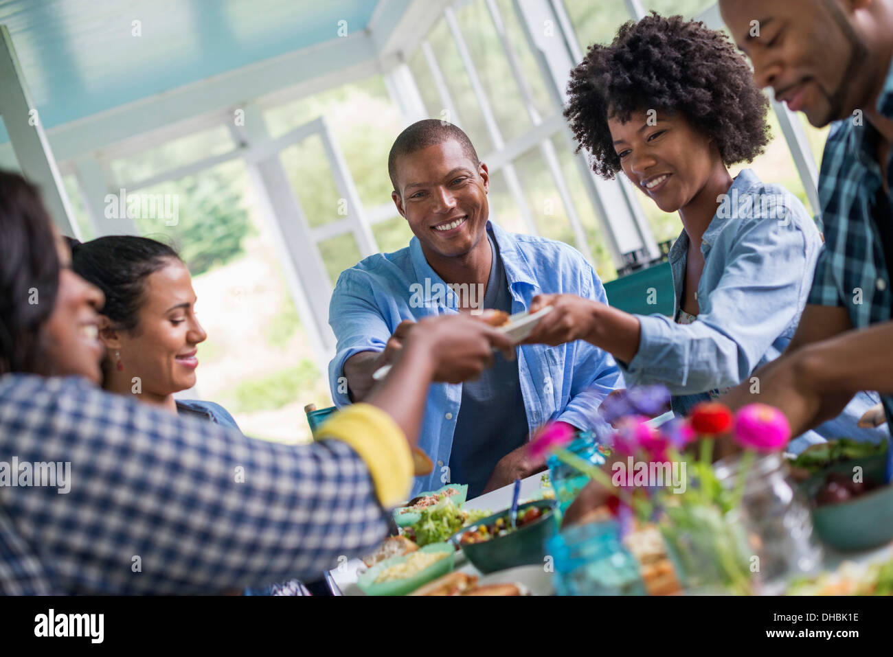 Eine Gruppe von Frauen und Männern an einem Tisch, die gemeinsame Mahlzeit in einer Landhausküche. Stockfoto