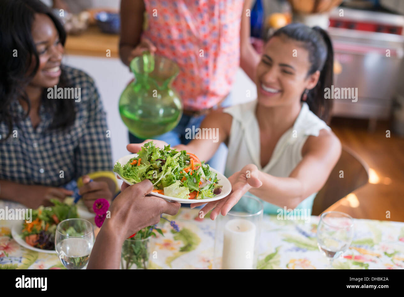 Eine Gruppe von Frauen und Männern bei einer Mahlzeit in einer Landhausküche. Stockfoto