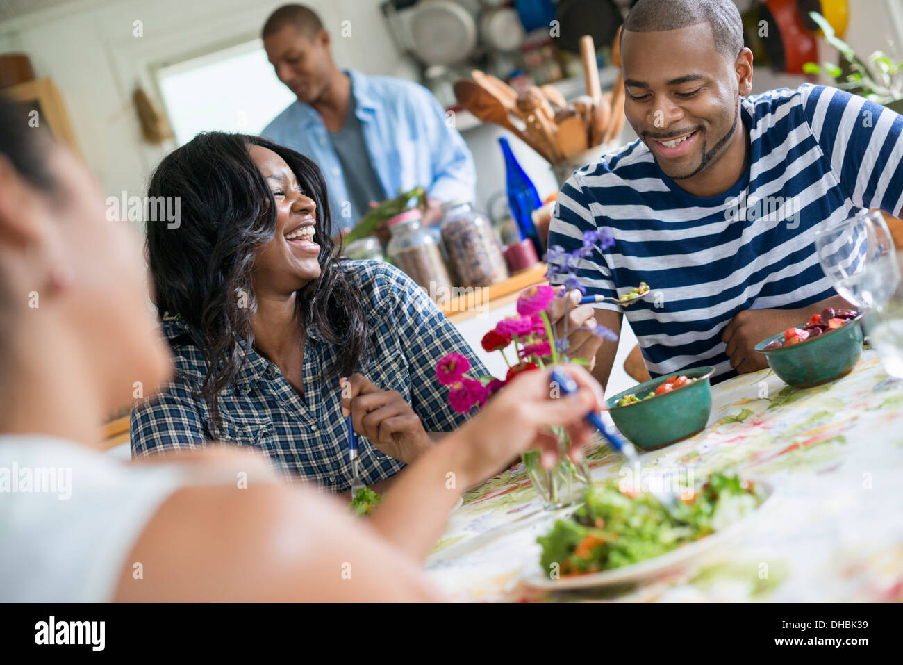 Eine Gruppe von Frauen und Männern bei einer Mahlzeit in einer Landhausküche. Stockfoto