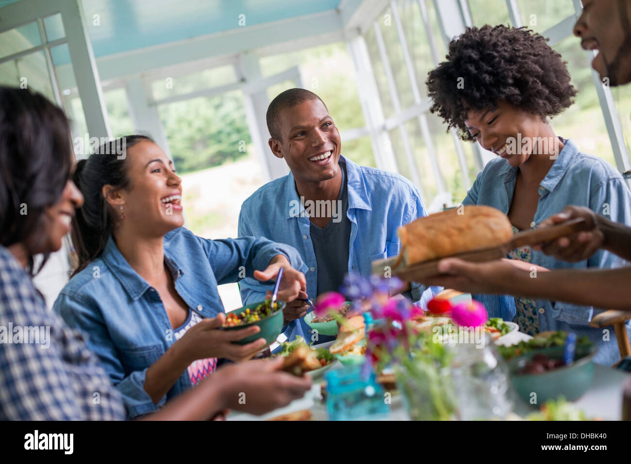 Eine Gruppe von Frauen und Männern an einem Tisch, die gemeinsame Mahlzeit in einer Landhausküche. Stockfoto
