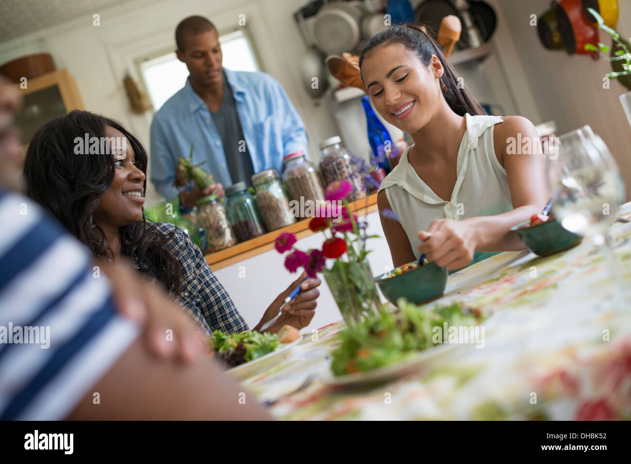 Eine Gruppe von Frauen und Männern bei einer Mahlzeit in einer Landhausküche. Stockfoto