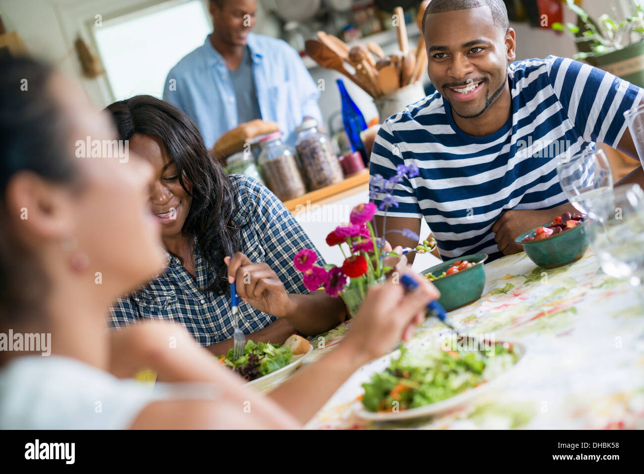 Eine Gruppe von Frauen und Männern bei einer Mahlzeit in einer Landhausküche. Stockfoto