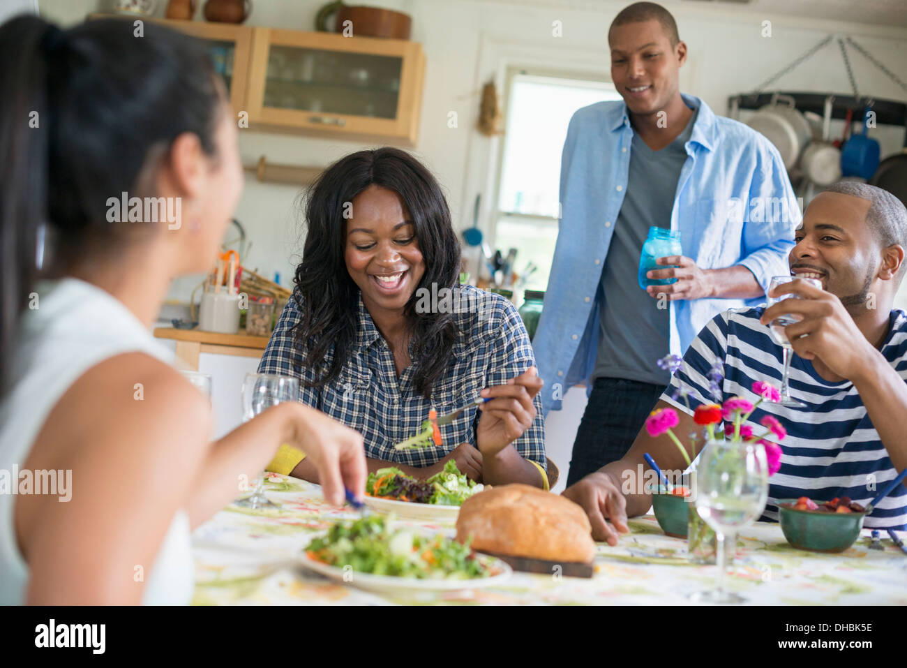 Eine Gruppe von Frauen und Männern bei einer Mahlzeit in einer Landhausküche. Stockfoto