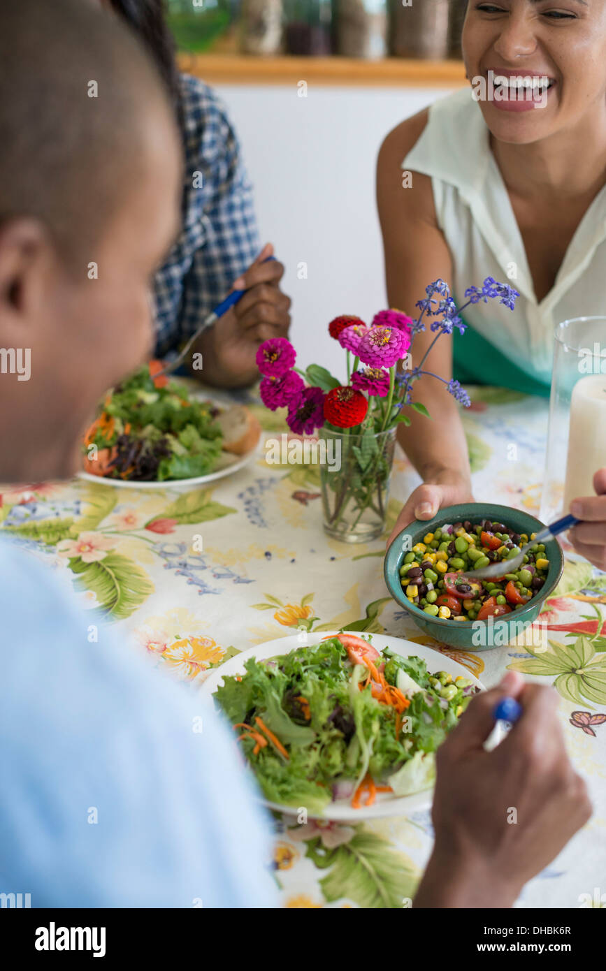 Eine Gruppe von Frauen und Männern bei einer Mahlzeit in einer Landhausküche. Stockfoto