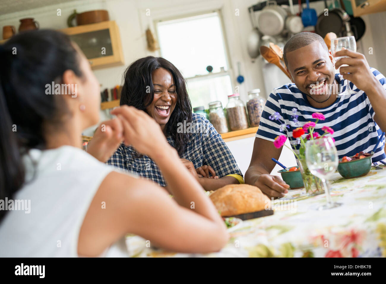 Eine Gruppe von Frauen und Männern bei einer Mahlzeit in einer Landhausküche. Stockfoto
