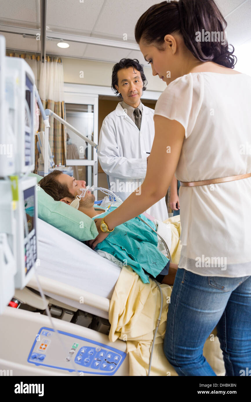 Arzt Frau Stand vom Patientenbett zu betrachten Stockfoto