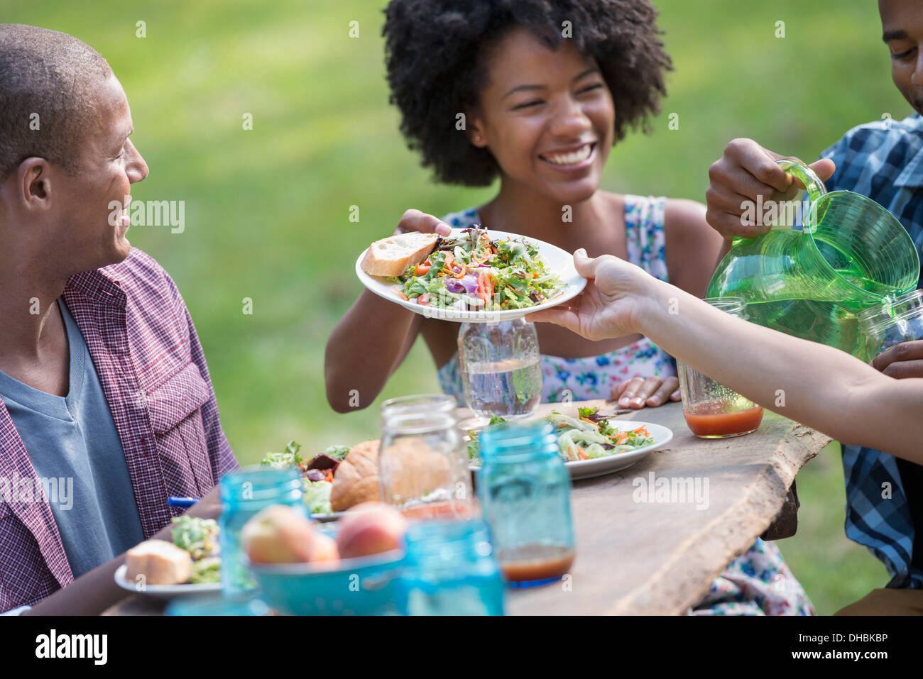 Eine Gruppe von Erwachsenen und Jugendlichen bei einer Mahlzeit im Garten eines Bauernhauses. Stockfoto