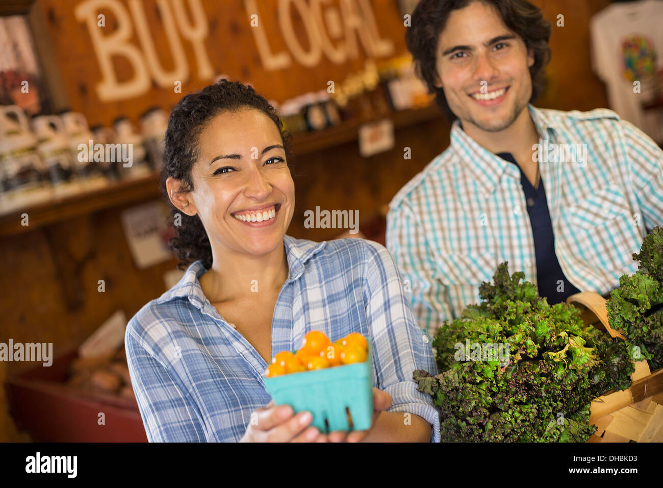 Zwei Personen mit Körben von Tomaten und geschweiften grünes Blattgemüse. Arbeiten auf einem Bio-Bauernhof. Stockfoto
