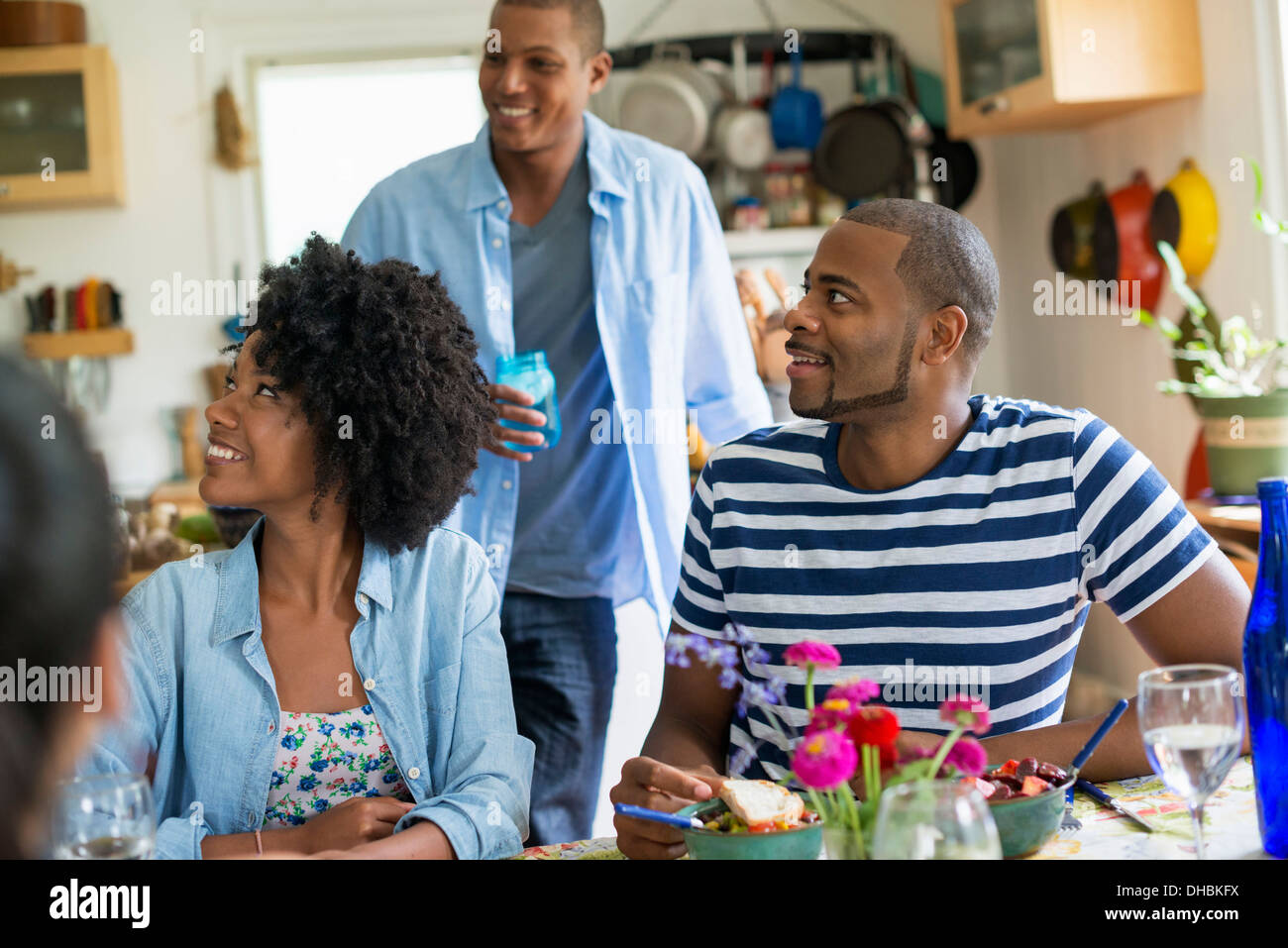 Eine Gruppe von Frauen und Männern bei einer Mahlzeit in einer Landhausküche. Stockfoto