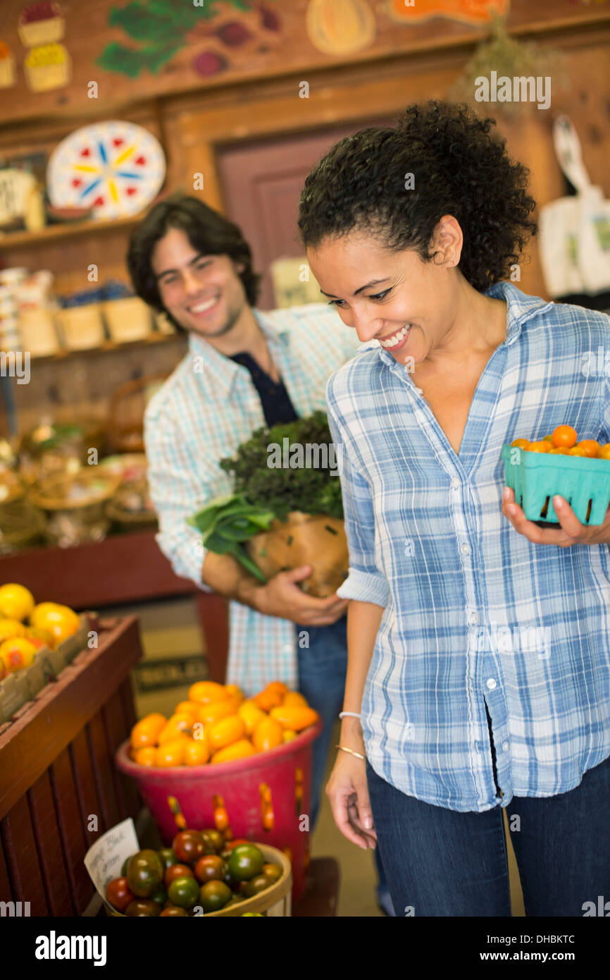 Zwei Personen mit Körben von Tomaten und geschweiften grünes Blattgemüse. Arbeiten auf einem Bio-Bauernhof. Stockfoto