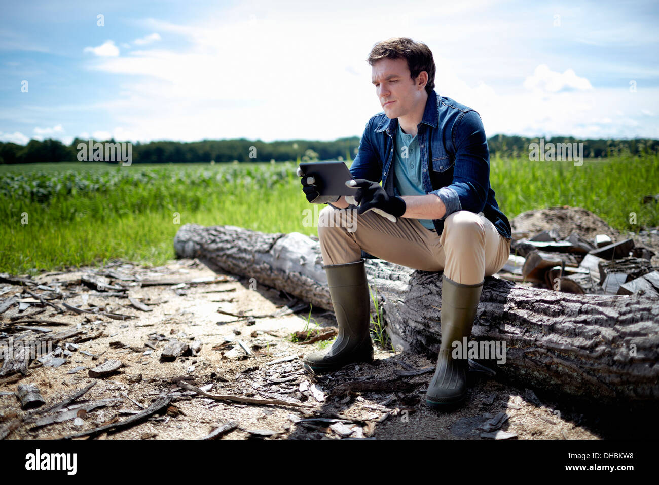 Ein Bauer sitzt mit einem Tablet-Computer im Freien in einem Feld von Pflanzen Stockfoto