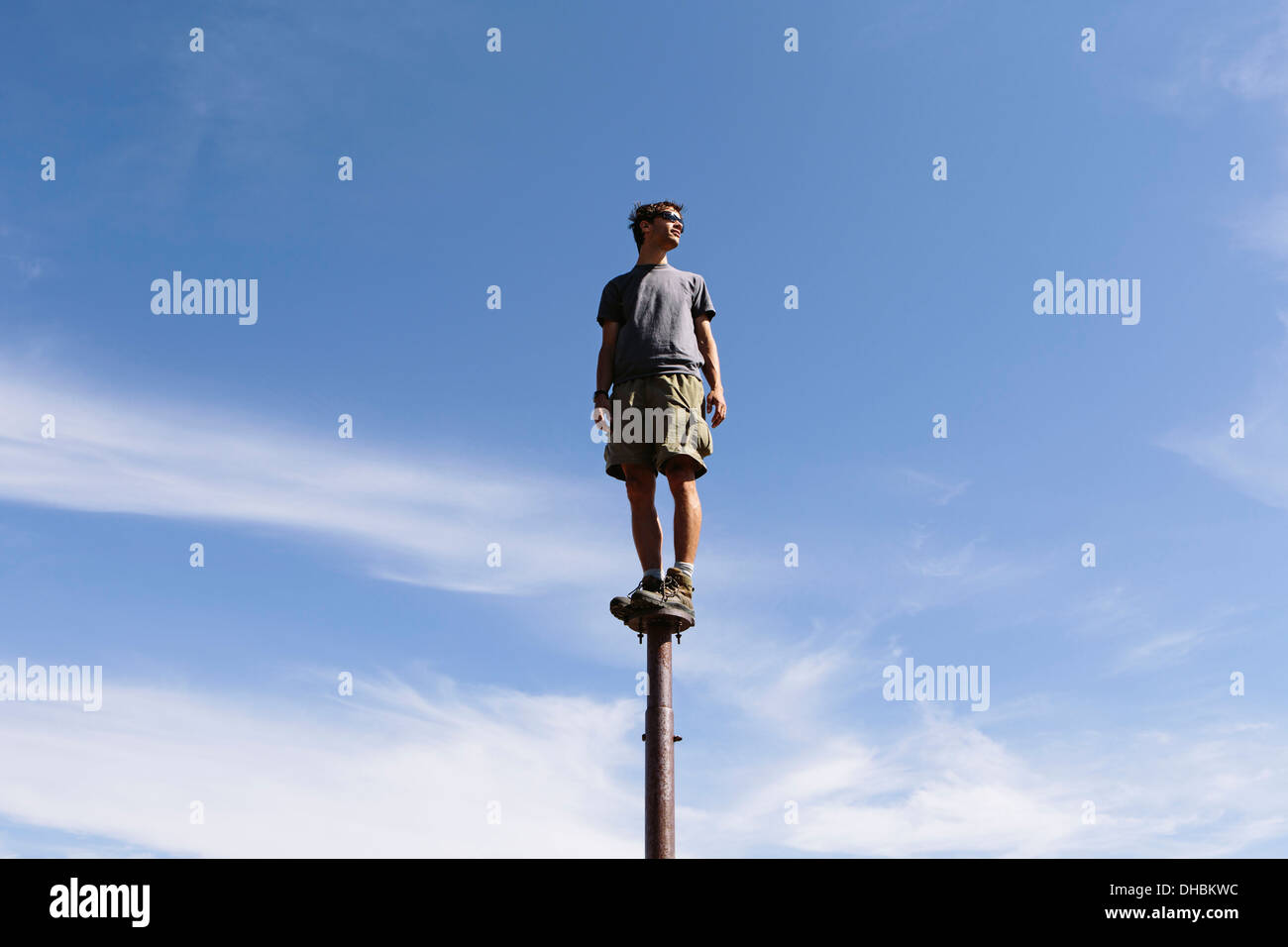 Mann stehend balancieren auf Metallpfosten mit Blick auf den weiten Himmel Überraschung Gebirge alpinen Seen Wildnis Mt Stockfoto