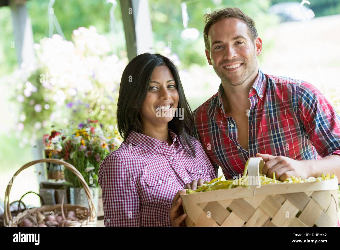 Ein Bauernhof Stand mit frischem Bio-Gemüse und Obst.  Ein Mann und eine Frau mit Körben von Bohnen. Stockfoto
