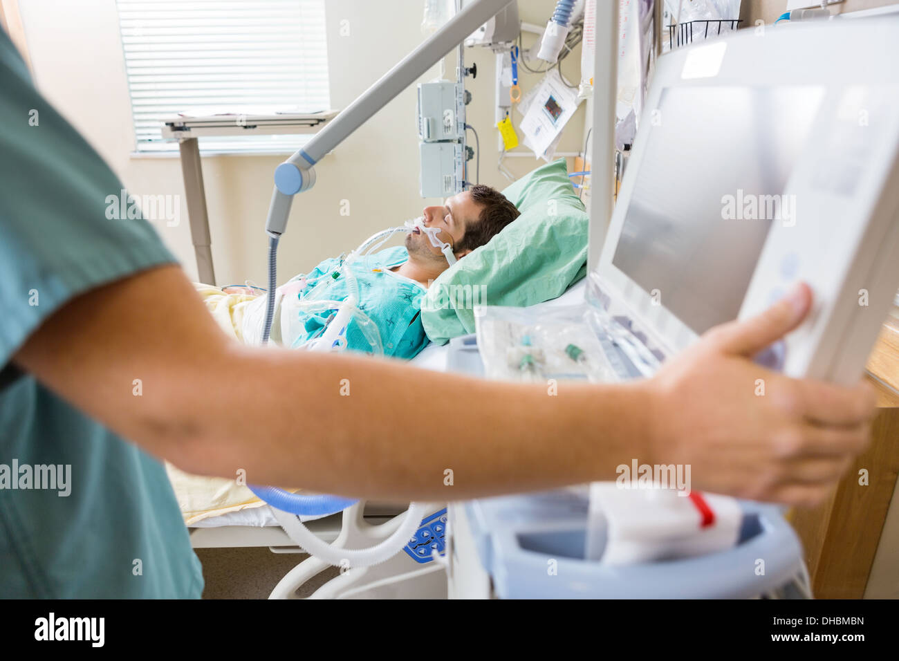 Krankenschwester Pressen Monitortaste mit Patienten auf Bett liegend Stockfoto
