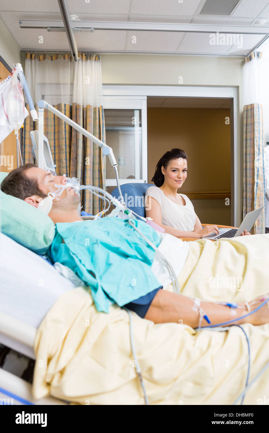 Frau mit Laptop sitzen von Patienten im Krankenhaus Stockfoto