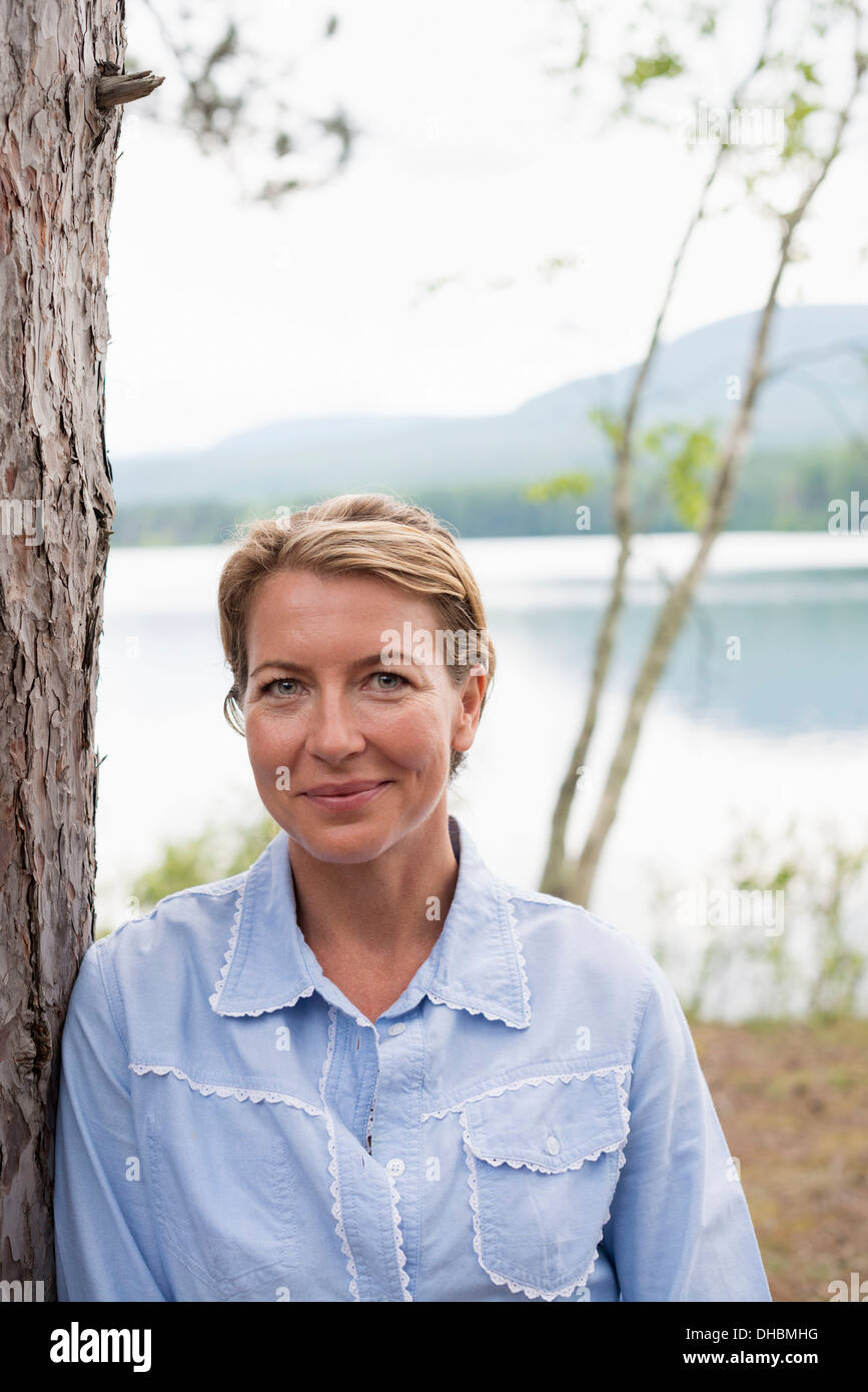 Eine Frau stand unter den Bäumen am Ufer eines Sees im Staat New York. Stockfoto