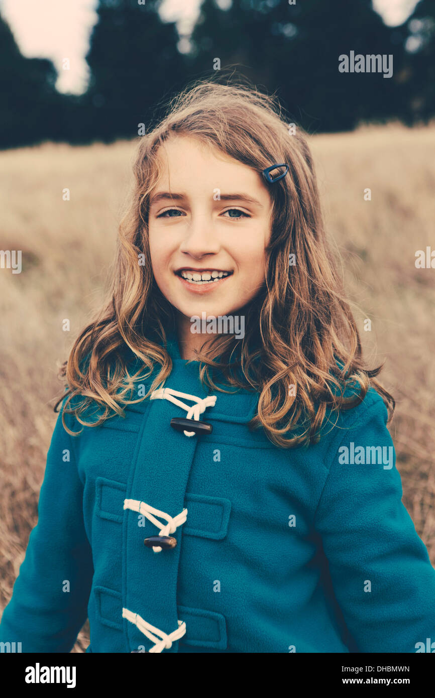 Ein junges Mädchen von neun Jahre alt, in einem blauen Dufflecoat lächelnd in die Kamera. Stockfoto