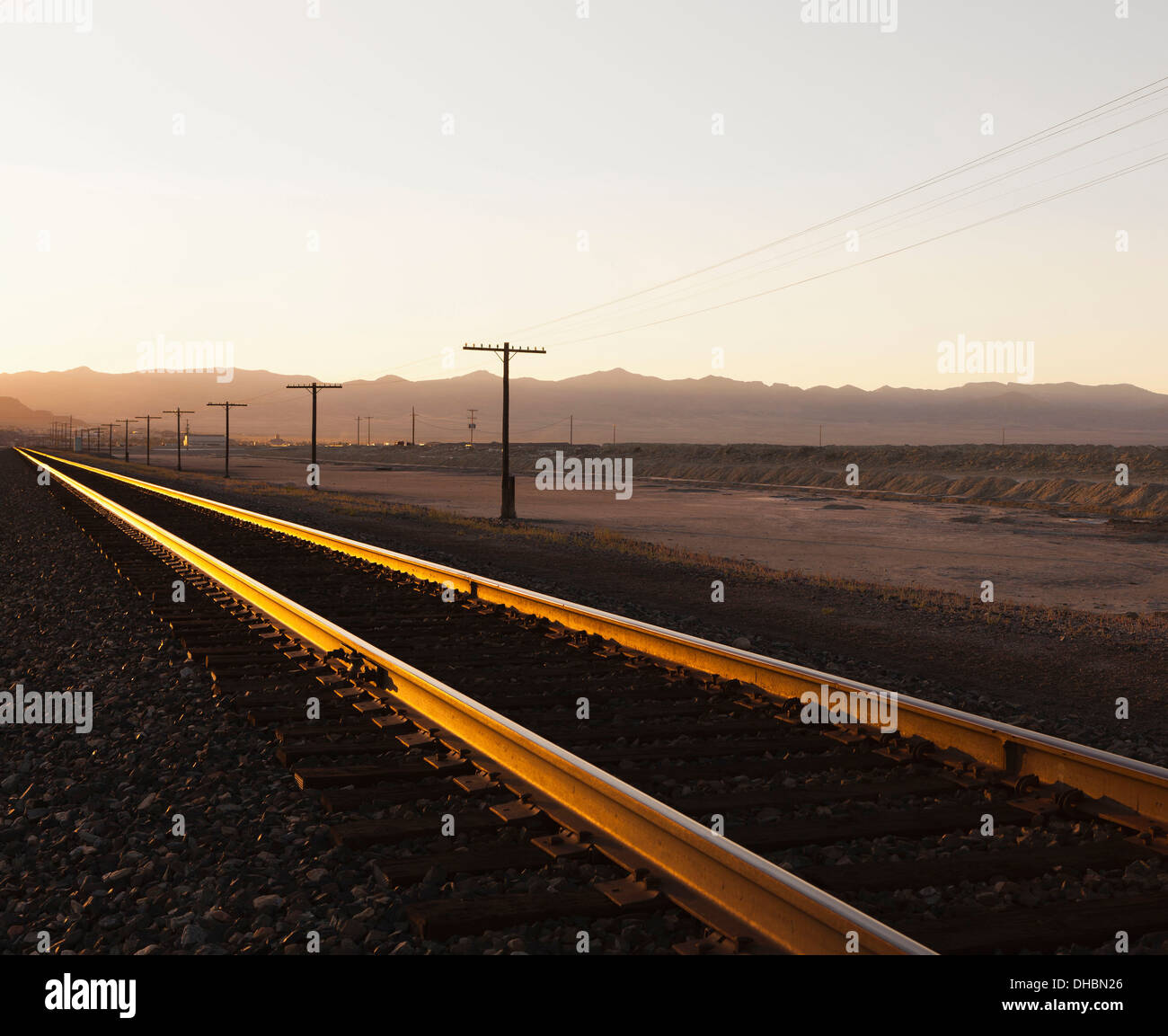 Eisenbahnschienen erstreckt sich über die flache Wüstenlandschaft von Utah in der Abenddämmerung. Stockfoto
