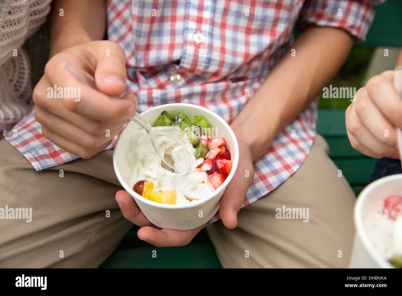 Junge Leute sitzen nebeneinander, Essen frisches Bio-Obst und Joghurt Wüste. Stockfoto