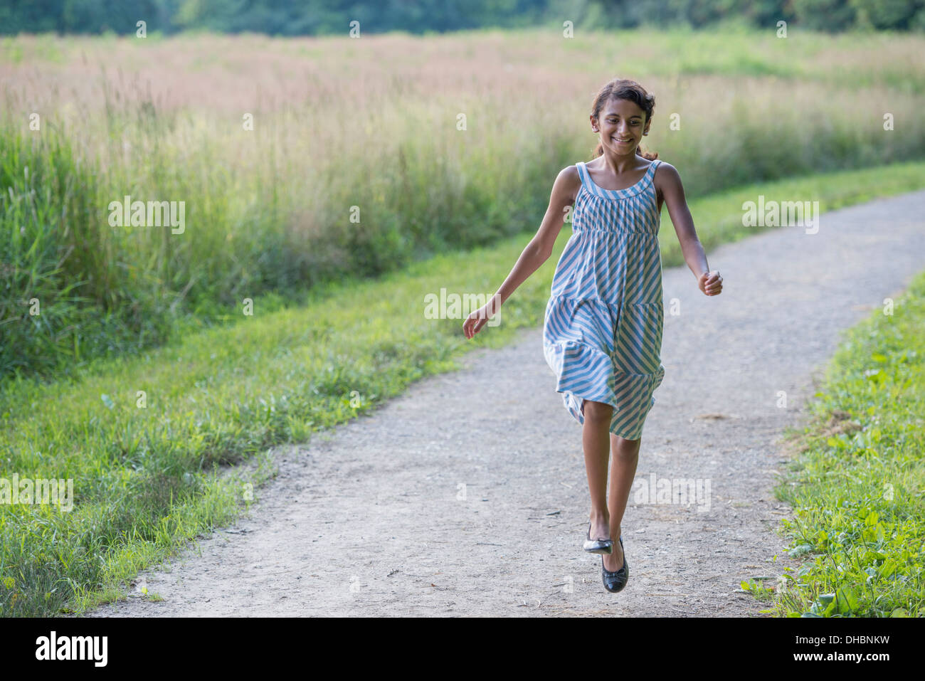 Ein junges Mädchen in einem Sommerkleid, zu Fuß entlang eines Pfades. Stockfoto