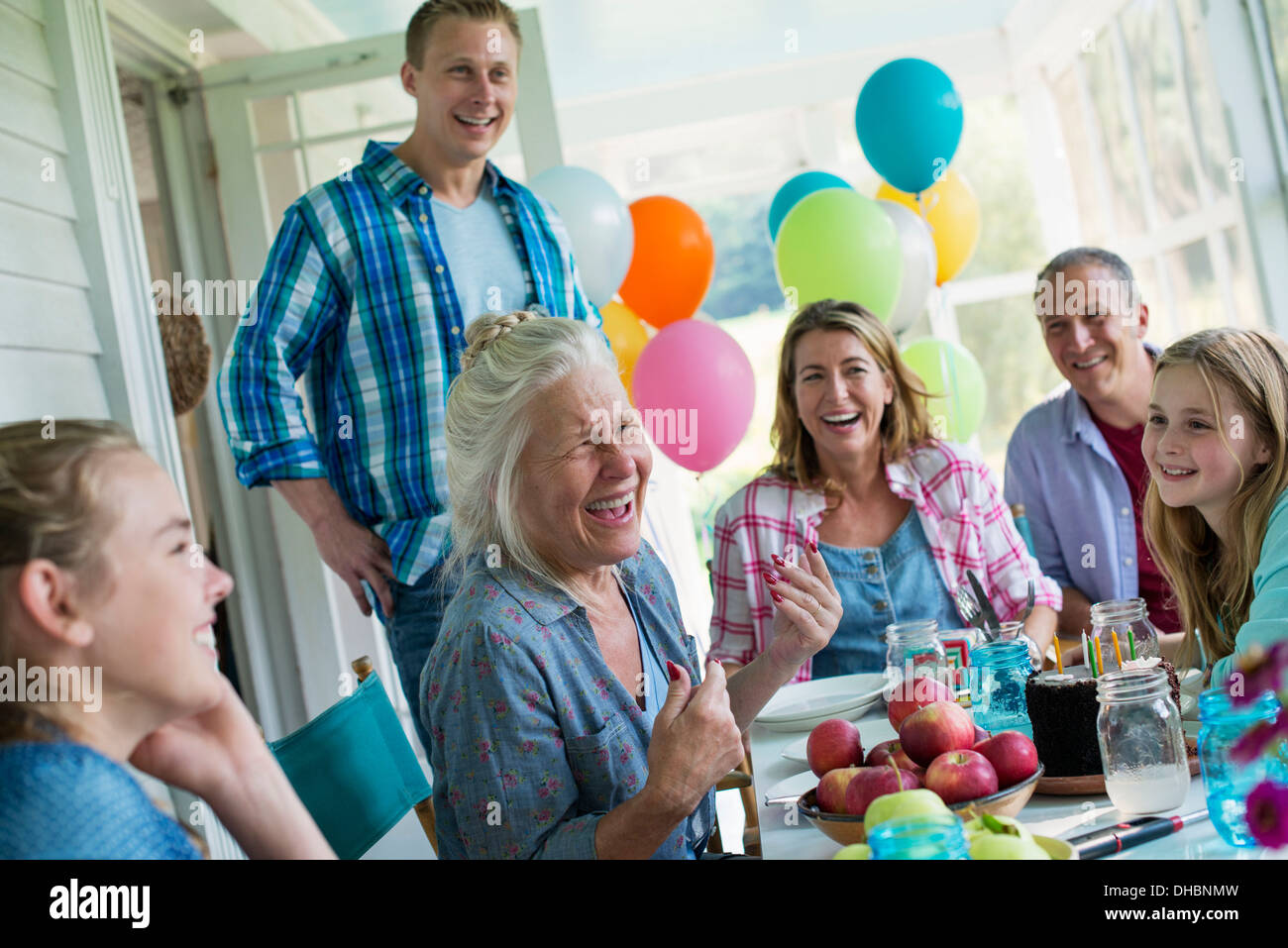 Eine Geburtstagsfeier in einer Landhausküche. Eine Gruppe von Erwachsenen und Kinder versammelten sich um einen Schokoladenkuchen. Stockfoto