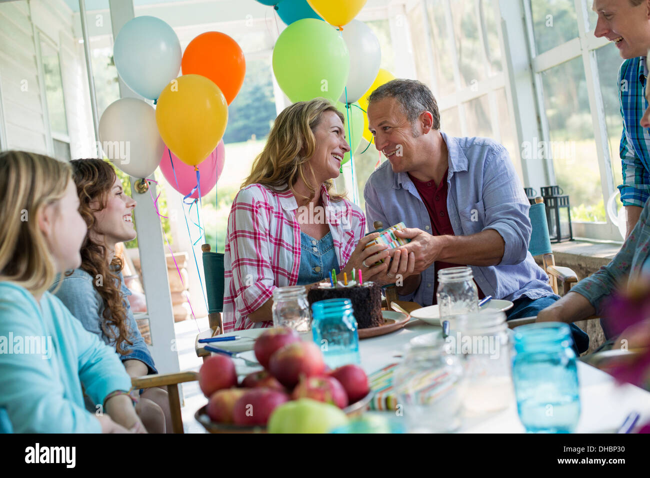 Eine Geburtstagsfeier in einer Landhausküche. Eine Gruppe von Erwachsenen und Kinder versammelten sich um einen Schokoladenkuchen. Stockfoto