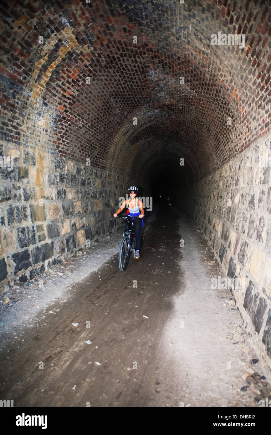 Fahrrad fahren durch die Preise Creek Tunnel, Neuseelands Otago Central Rail Trail; Otago, Neuseeland Stockfoto