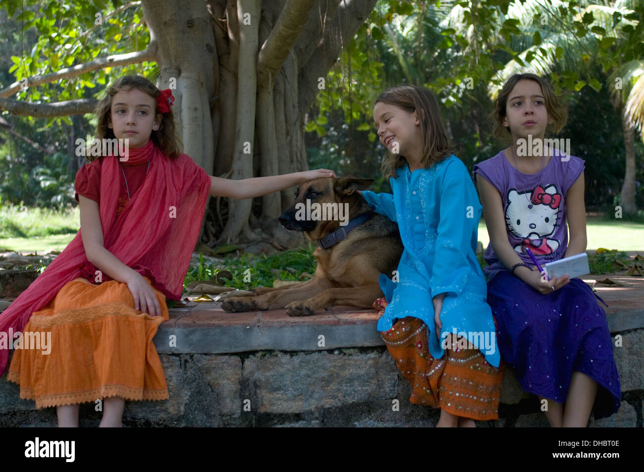 Drei bunt gekleidete Schwestern am saß unter einem jungen Banyanbaum mit einer Deutsch-elsässischen in Puttaparthi Andhara Pradesh Sout Stockfoto